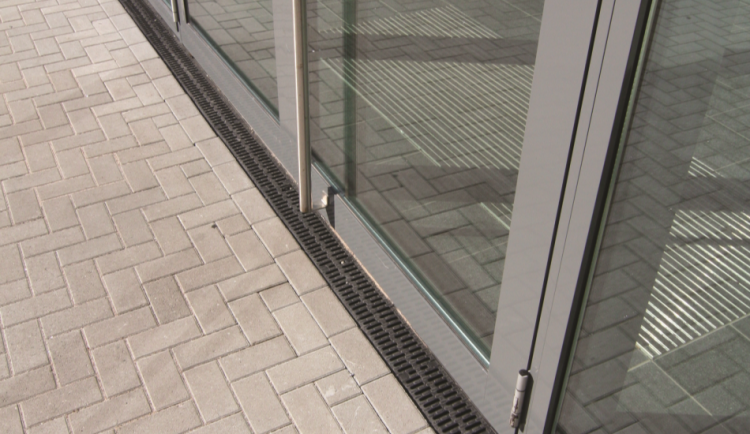 anal XTRADRAIN 100 con reja pasarela de composite delante de la puerta de un edificio